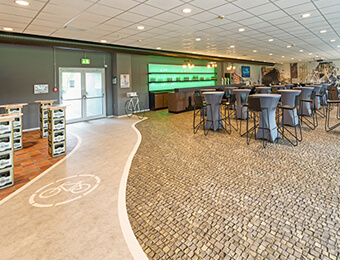 VIP Tribüne im Preussen Stadion mit FOTOBODEN™ in Objektqualität ausgestattet. Fahrradweg und Kopfsteinpflaster wurden individuell auf den Vinylboden gedruckt.
